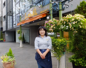 新横浜駅からもほど近いケーキ工房ラピエスモンテ。隣は新横浜グレイスホテル（奥側）、向かいは新横浜プリンスぺぺ（左側）と、新横浜訪問には絶好の立地。嶋崎さんはこの場所の花の管理も行っている