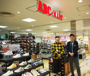 この3月で2周年を迎えたABCマート（ABC-MART）日吉東急アベニュー店の宮本昌英ストアマネージャー（左）。日吉東急アベニューの元林正輝マネジャーと