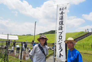 「鶴見川舟運復活プロジェクト」ののぼりの前で。副会長の大谷佐一さん（右）と世話人の臼井さん