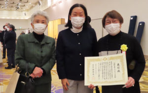 同じく「港北区民表彰」を受賞した「介護を考えるぶどうの会」は、小形晴身（はるみ）代表にかわり、宮澤よし子さんが表彰状を受け取り、メンバーとその喜びを分かち合っていました