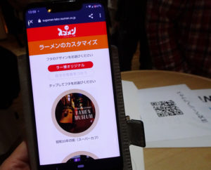フタのデザインにはアプリをダウンロードしたスマートフォン（スマホ）内の写真も使用可能。操作が苦手な場合や日本語が使えない人への対応に課題も