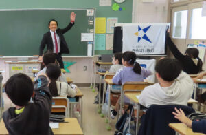 「背広」に着替えた小宮山さんが“夢の実現”に至るまでの道のりを子どもたちにもわかりやすく語り授業を進行していた