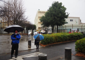 あいにくの雨天での「50周年デー」がスタート。館校長が校門前で子どもたちを笑顔で出迎えていました