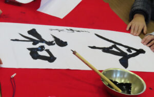 茂住さんが「令和」の文字を筆を執り子どもたちの眼前で披露